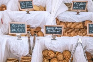 A variety of French biscuits displayed at an outdoor market with chalkboard labels.